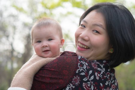 Foto de Joven feliz y hermosa asiática coreana mujer sosteniendo pequeña hija, un lindo un adorable bebé niña, juguetón juntos en el parque en madre e hijo amor y crianza concepto - Imagen libre de derechos