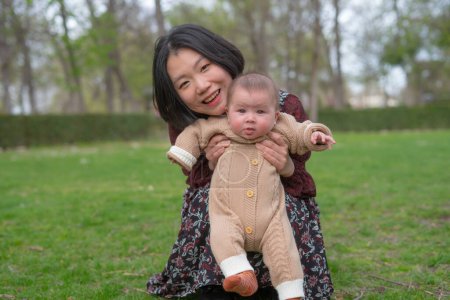 Photo for Young happy and beautiful Asian Korean woman holding little daughter, a cute an adorable baby girl, playful together in the park in mother and child love and parenting concept - Royalty Free Image