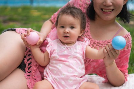 Foto de Mamá asiática y niño pequeño - joven mujer china feliz y hermosa jugando en el parque de la ciudad con adorable y alegre niña en el amor de la madre y la hija y la vinculación - Imagen libre de derechos