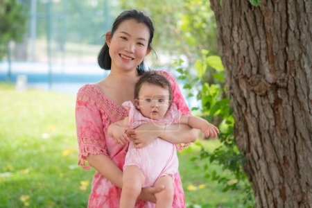 Photo for Asian mum and little child - young happy and beautiful Korean woman playing on city park with adorable and cheerful baby girl in mother and daughter love and bonding - Royalty Free Image
