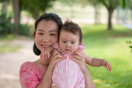 Foto de Mamá asiática y niño pequeño - joven mujer coreana feliz y hermosa jugando en el parque de la ciudad con adorable y alegre niña en el amor de la madre y la hija y la vinculación - Imagen libre de derechos