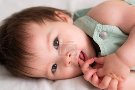 Photo for Mixed ethnicity Asian Caucasian 8 months baby girl - lifestyle home portrait of adorable and happy female child lying playful on bed exploring the surroundings curious - Royalty Free Image