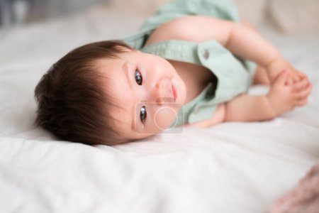 Foto de Etnia mixta Asiática Caucásica 8 meses bebé niña - estilo de vida retrato en casa de adorable y feliz niña acostada juguetona en la cama explorando los alrededores curioso - Imagen libre de derechos