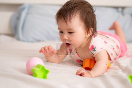 Foto de Estilo de vida casa retrato de dulce y adorable etnia mixta asiático caucásico bebé jugando con bloques de color en la cama emocionado y feliz en concepto de la infancia - Imagen libre de derechos