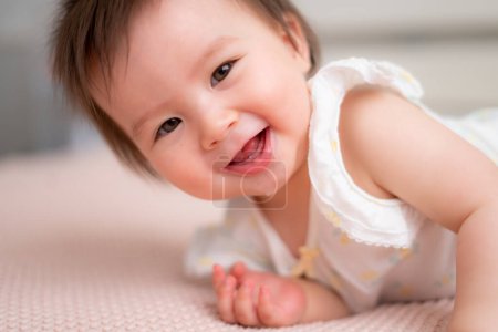 Photo for Lifestyle home portrait of 9 months old mixed ethnicity Asian Caucasian baby girl playing happy and carefree on bed crawling laughing and excited in childhood and nursery concept - Royalty Free Image
