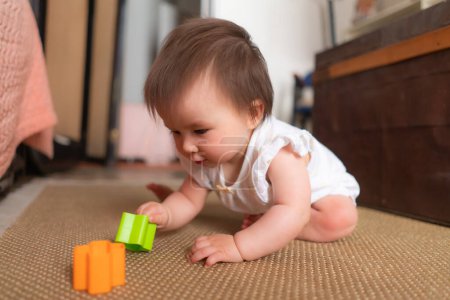Foto de Estilo de vida casa retrato de adorable y hermosa asiática caucásica mezclado bebé jugando en el suelo con bloques de color emocionado y feliz en concepto de la infancia - Imagen libre de derechos