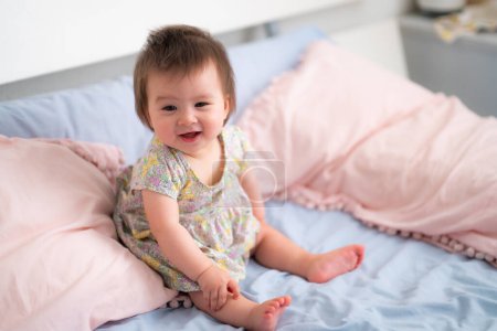 Photo for Lifestyle home portrait of happy and adorable 9 months old mixed ethnicity Asian Caucasian baby girl playing cheerful and carefree on bed looking sweet and cute in childhood concept - Royalty Free Image
