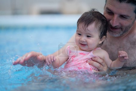 Photo for Lifestyle portrait of father and little daughter enjoying summer - man holding her sweet baby girl excited and cheerful playing together at resort swimming pool in parenting concept - Royalty Free Image