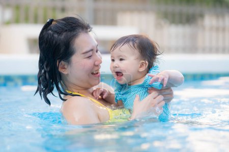 Photo for Happy and beautiful Asian woman holding her little baby girl playful - Korean mother and adorable daughter playing on water at resort swimming pool in Summer - Royalty Free Image