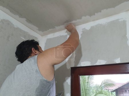 Foto de Preparación de yeso y pintura mural. Masculino asiático aplicando yeso o relleno de parche de paneles de yeso. Bricolaje - Imagen libre de derechos