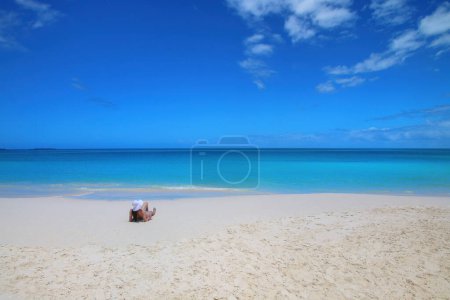 Woman relaxing on Fayaoue beach on the coast of Ouvea lagoon, Mouli and Ouvea Islands, New Caledonia. The lagoon was listed as Unesco World Heritage site in 2008.