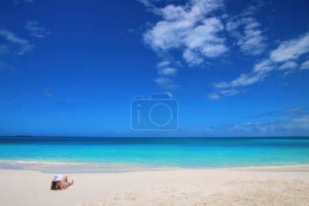 Woman relaxing on Fayaoue beach on the coast of Ouvea lagoon, Mouli and Ouvea Islands, New Caledonia. The lagoon was listed as Unesco World Heritage site in 2008.