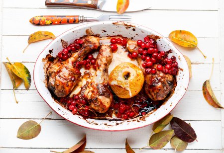 Grilled spicy chicken legs baked with apples and berries. Fried chicken meat