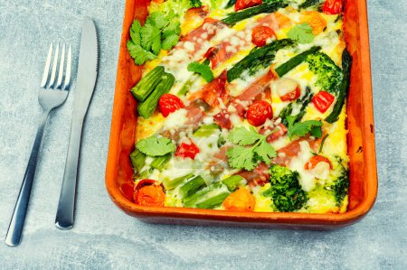 Téléchargez les photos : Asperges enveloppées dans du bacon, cuites avec des tomates et du brocoli iv plat de casserole. Aliments biologiques - en image libre de droit