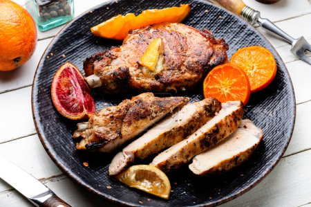 Téléchargez les photos : Barbecue de steak de viande cuit dans des oranges. Découpe en tranches de steak sur le flanc. Viande dans la marinade d'agrumes - en image libre de droit