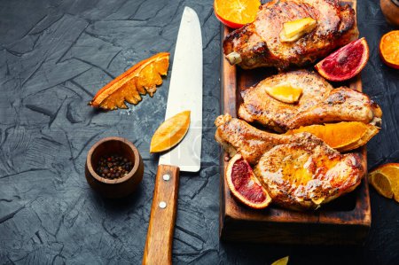 Téléchargez les photos : Steak de viande cuit dans des oranges sur une planche à découper en bois. Viande dans la marinade d'agrumes - en image libre de droit