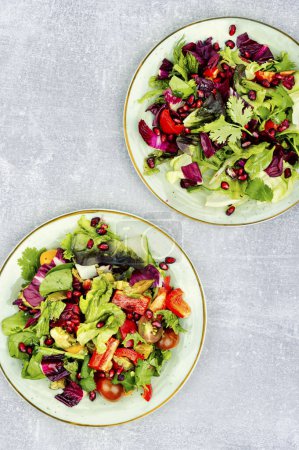 Photo for Summer salad with greens, pepper, red lettuce and cucumber, decorated with pomegranate. Flat lay - Royalty Free Image