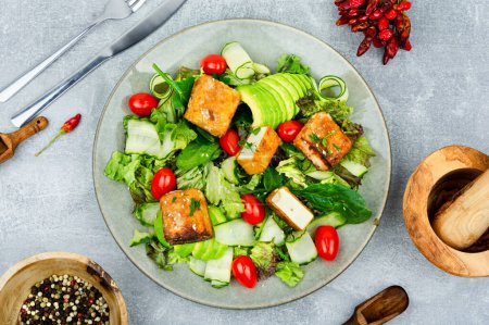 Photo for Appetizing lettuce salad, cucumber, avocado and breaded fried tofu soy cheese. Healthy lifestyle - Royalty Free Image