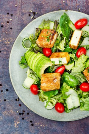 Photo for Vegan salad with cucumber, avocado and roasted tofu soy cheese in a plate. Vegetarian cuisine,top view - Royalty Free Image