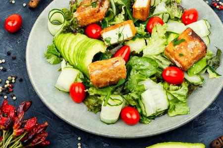 Photo for Fresh summer salad with greens, cucumber, avocado, tomatoes and breaded fried tofu cheese. Vegetarian food - Royalty Free Image