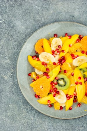 Photo for Salad of mango, citrus, banana and berries in a bowl. Healthy fresh fruit salad - Royalty Free Image
