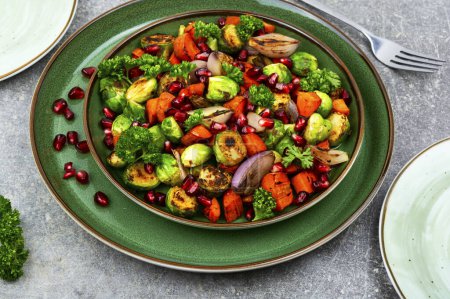 Photo for Salad with Brussels sprouts, carrots, garnished with greens and pomegranate on a green plate - Royalty Free Image