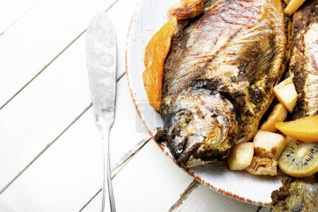 Téléchargez les photos : Appetizing river carp baked with fruits. Grilled fish - en image libre de droit