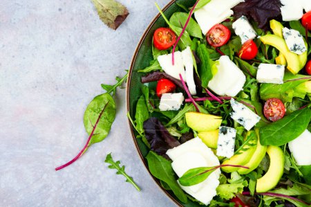 Foto de Salad with fresh lettuce, greens, avocado, tomatoes and cheeses. Top view. Copy space - Imagen libre de derechos