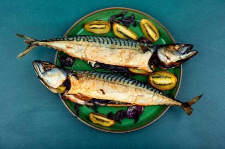 Téléchargez les photos : Two appetizing mackerel fish baked with kiwi pieces. Top view - en image libre de droit