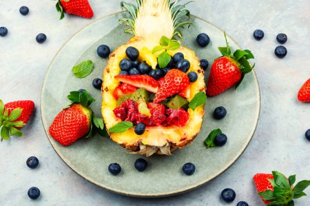 Foto de Fruit salad of strawberries, kiwi, berries and orange in juicy pineapple. Concept of low calorie delicious desserts - Imagen libre de derechos