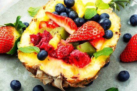 Foto de Tasty summer salad of strawberries, kiwi, berries and orange in half a pineapple. Close up - Imagen libre de derechos