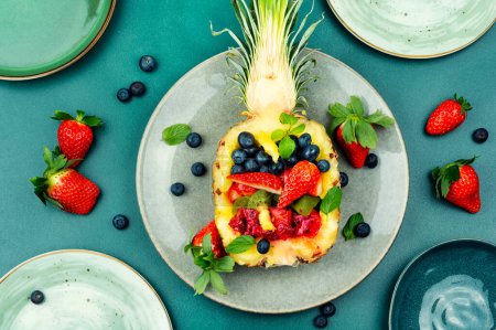 Foto de Fresh fruit salad with strawberry, pineapple, kiwi, ananas and mint served in half pineapple. Diet healthy food - Imagen libre de derechos