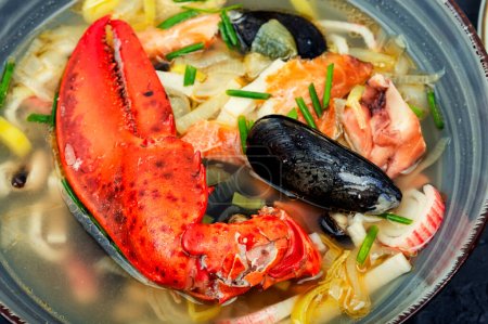 Photo for Seafood soup with lobster, mussels, shrimps and fish. Soup in ceramic bowl. Tom yum, close up - Royalty Free Image
