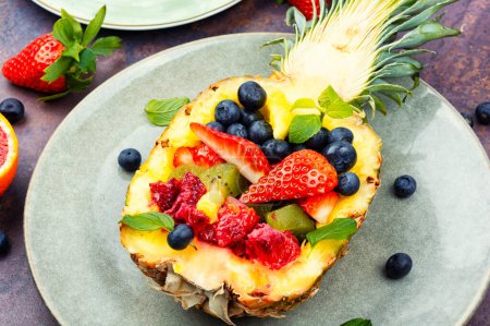 Photo for Fruit salad of strawberries, kiwi, berries and orange in half a pineapple. Vegetarian concept. - Royalty Free Image