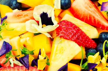Téléchargez les photos : Salade d'ananas, fraises et baies, décorée de fleurs. Contexte alimentaire. - en image libre de droit