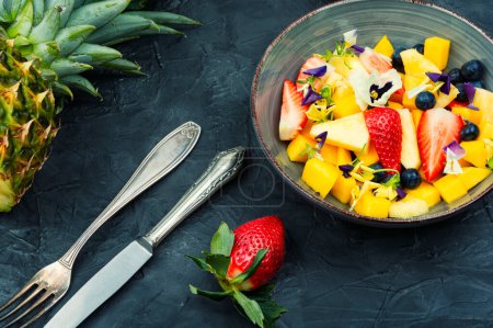 Photo for Salad of pineapple, strawberries and berries, decorated with edible flowers. Clean ealthy eating - Royalty Free Image