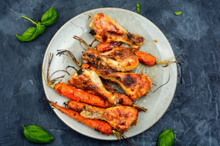 Téléchargez les photos : Jambes de poulet savoureux préparés avec des carottes sur l'assiette. - en image libre de droit