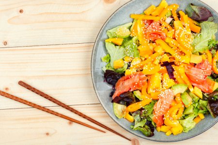 Photo for Tasty salad with salmon, mango, sesame avocado and pepper. Healthy eating, space for text. Food and chopsticks - Royalty Free Image