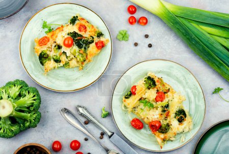Photo for Appetizing potato gratin with broccoli and tomatoes on a plate. Top view. - Royalty Free Image