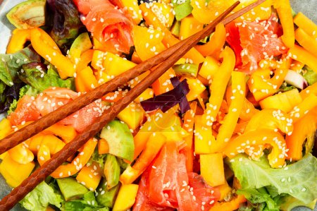 Téléchargez les photos : Salade asiatique au saumon fumé, mangue, sésame et légumes. Gros plan. - en image libre de droit
