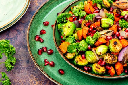 Téléchargez les photos : Salade aux légumes grillés, décorée de légumes verts et grenade sur une assiette verte. Légumes BBQ - en image libre de droit