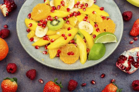 Téléchargez les photos : Salade de mangue, agrumes, banane et baies dans un bol. Faire une salade de fruits - en image libre de droit