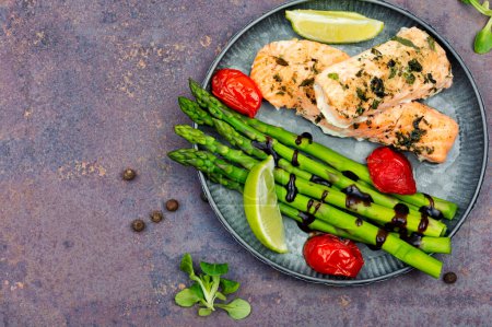 Photo for Tasty dish of trout, asparagus and tomato. Baked salmon. Space for text. - Royalty Free Image