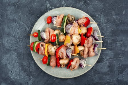 Foto de Kebab de carne fresca con verduras marinadas en hierbas sobre una mesa de cocina de hormigón. Vista superior. - Imagen libre de derechos