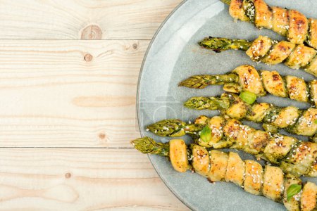 Photo for Green asparagus baked in dough with pesto sauce on a wooden rustic table. Copy space. - Royalty Free Image
