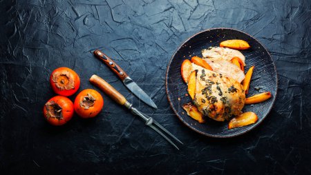 Foto de Pechuga de pollo asada con caqui en una mesa de cocina de hormigón. Copiar espacio, lugar de la receta. - Imagen libre de derechos