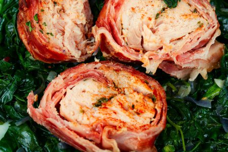 Photo for Grilled chicken fillet roll and fried spinach. Bacon wrapped chicken rolls. Close up - Royalty Free Image
