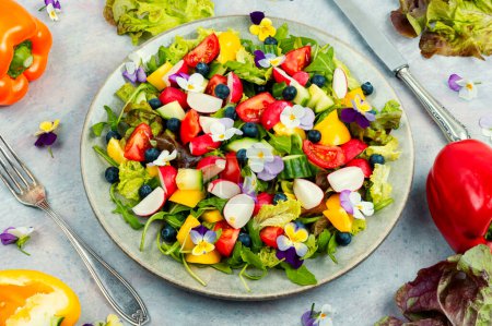 Grüner Salat auf einem Teller mit blühenden Stiefmütterchen. Gesunde Ernährung.