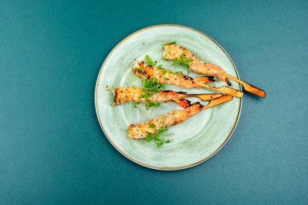 Téléchargez les photos : Savoureux barbecue aux crevettes ou langoustines aux herbes grillées sur bâtonnets de bois. - en image libre de droit