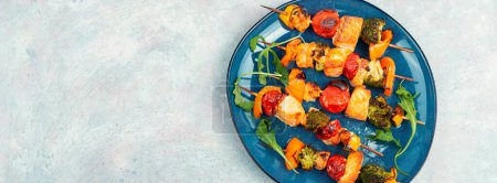 Foto de Brochetas de salmón de pescado y verduras en palo de madera. Kebab de mariscos. Copiar espacio. Banner largo. - Imagen libre de derechos